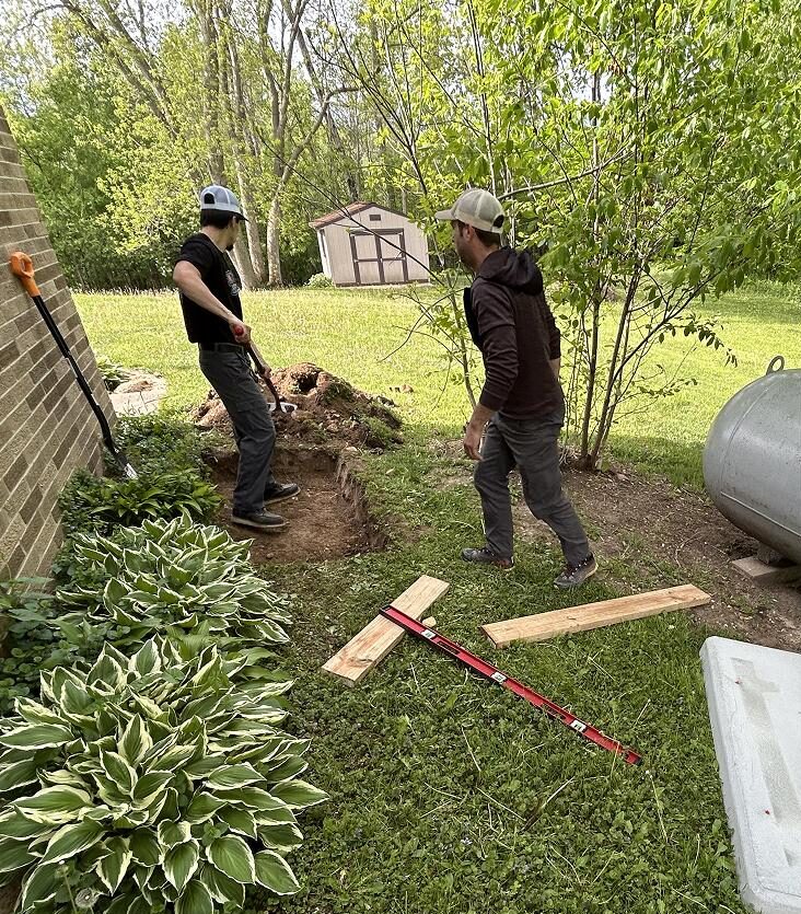 Two electricians preparing the ground for a standby generator installation at a residential property in Wisconsin
