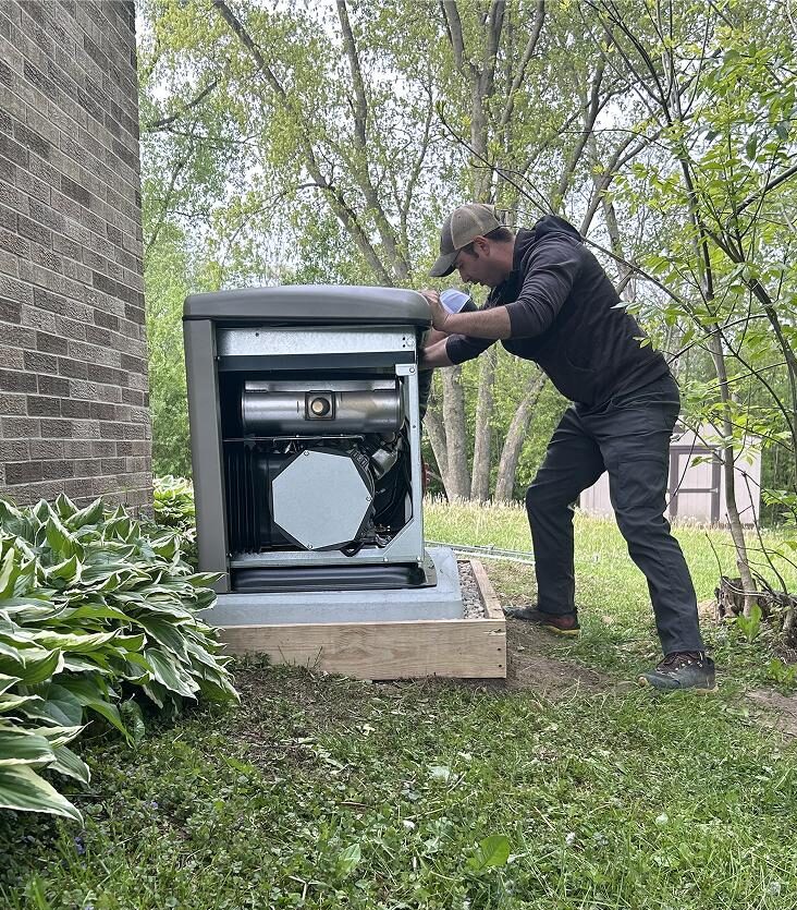 Electrician installing a standby generator next to a brick home in southeastern Wisconsin