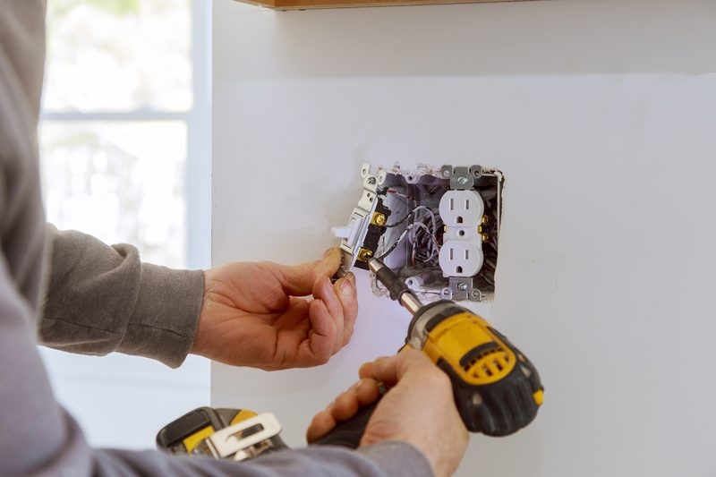 Electrician installing a light switch and outlet in a wall electrical box